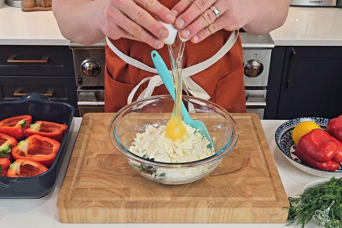 Someone cracking an egg in a large bowl with spinach and cottage cheese.