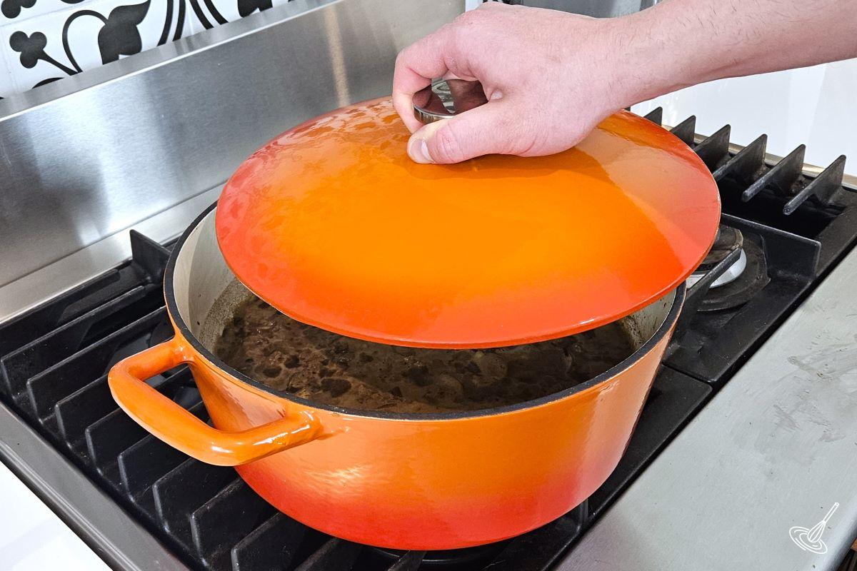 Someone placing the lid on a Dutch oven.