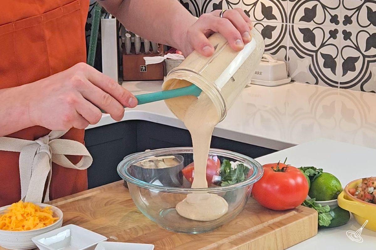 Someone pouring a taco dip mixture into a bowl. 