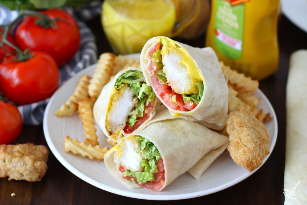 A Honey Mustard Chicken Wrap on a plate with a side of fries. 