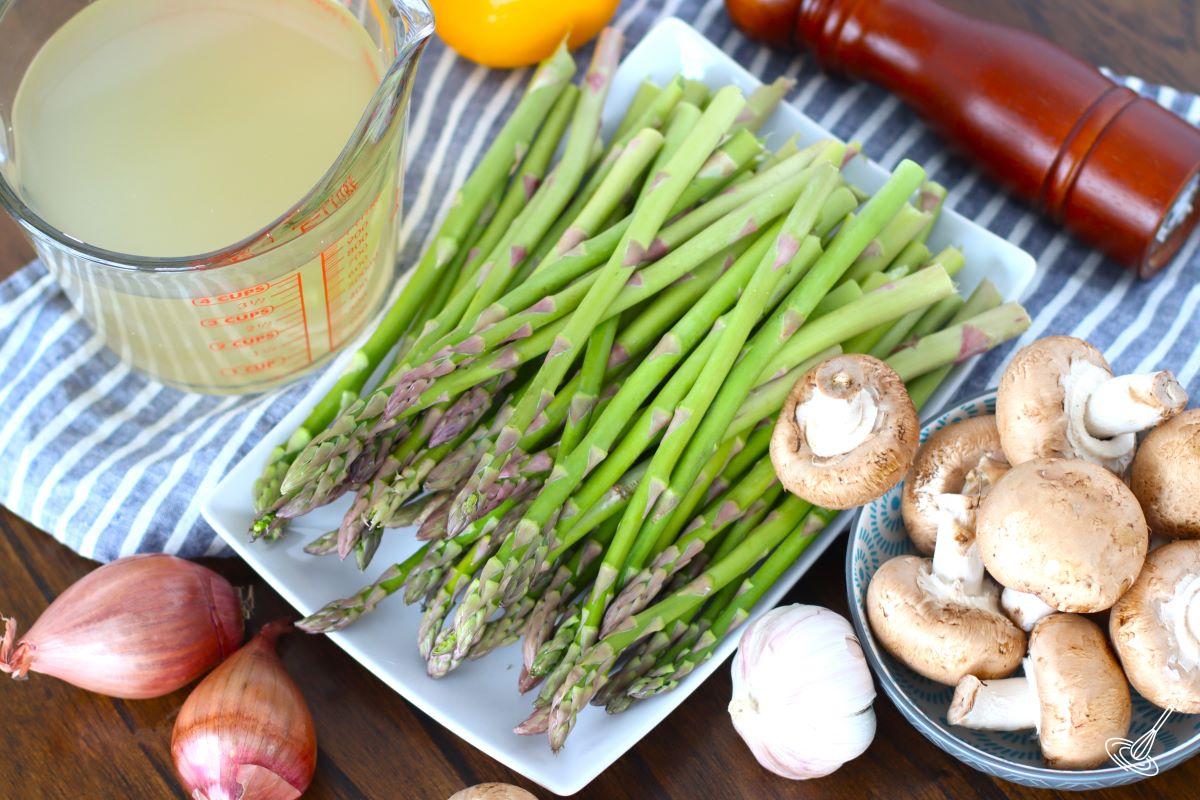 A plate of asparagus with a bowl of mushrooms on the table. 