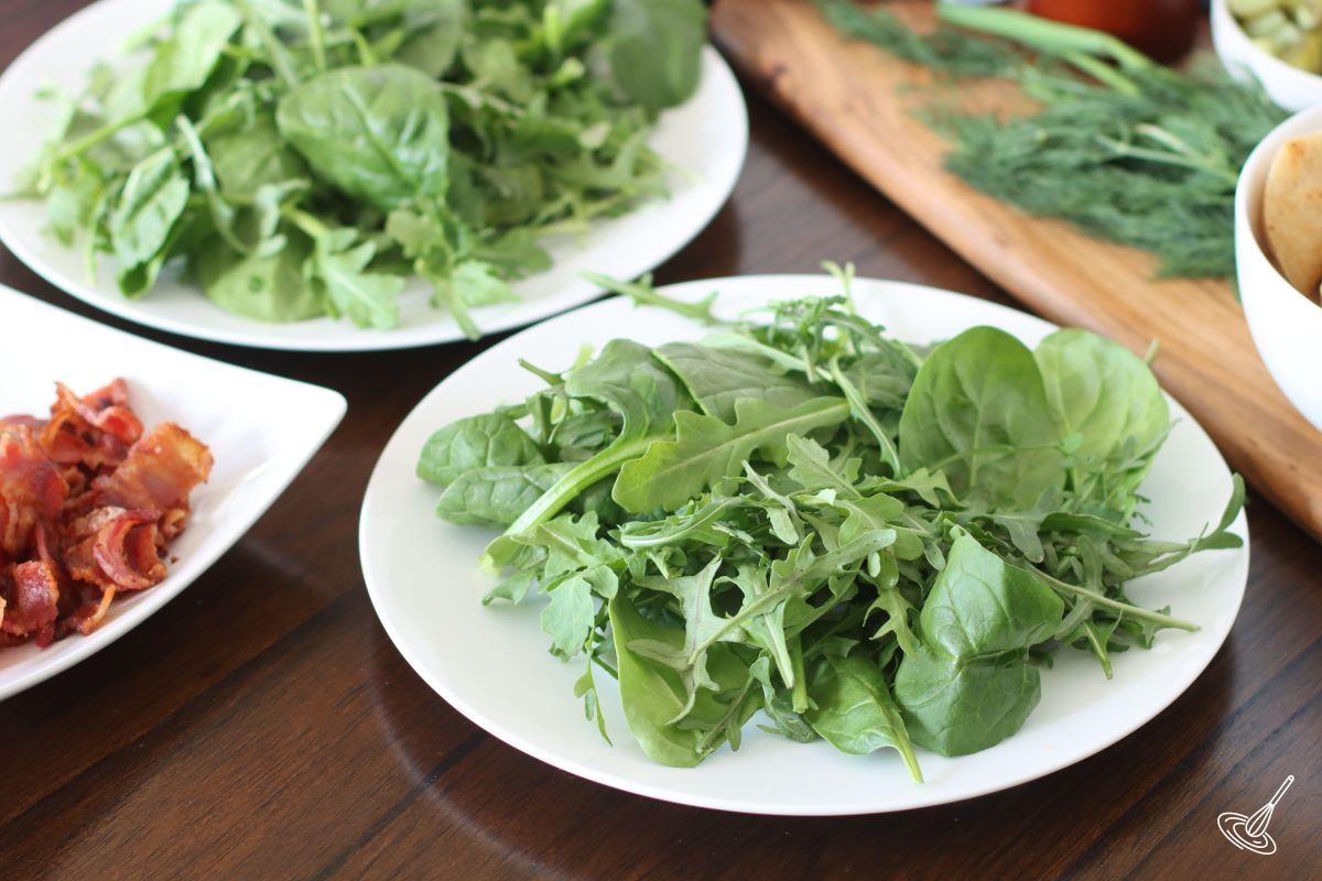Arugula and baby spinach on white plates. 