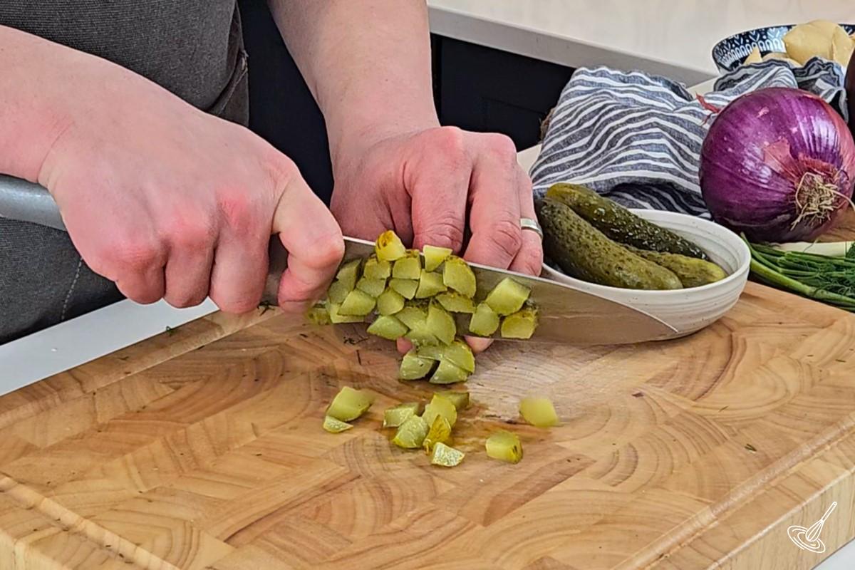 Someone chopping pickled on a cutting board.