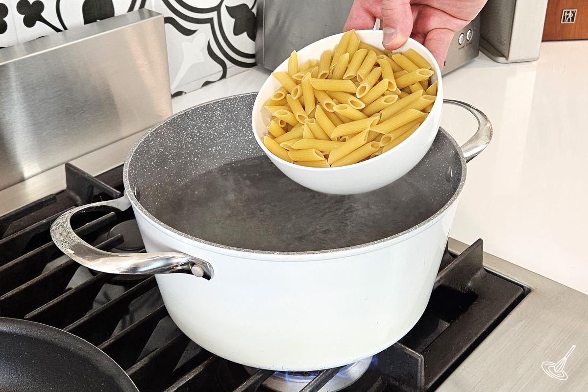 Someone placing pasta in a large pot of boiling water. 