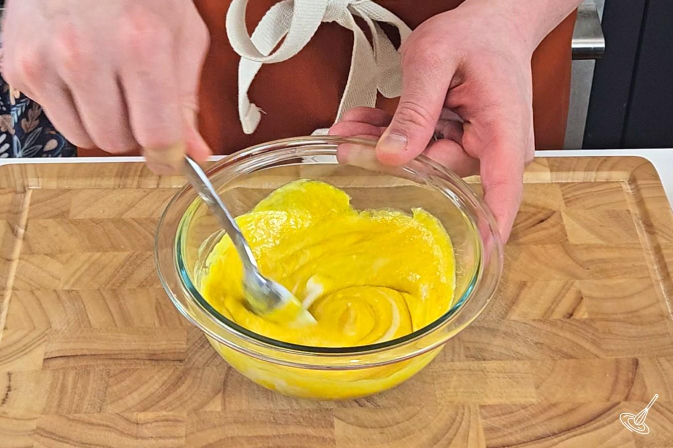 Someone stirring a bowl of honey mustard. 