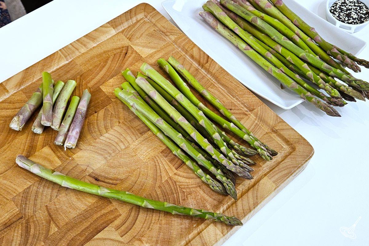Asparagus being trimmed on a cutting board. 
