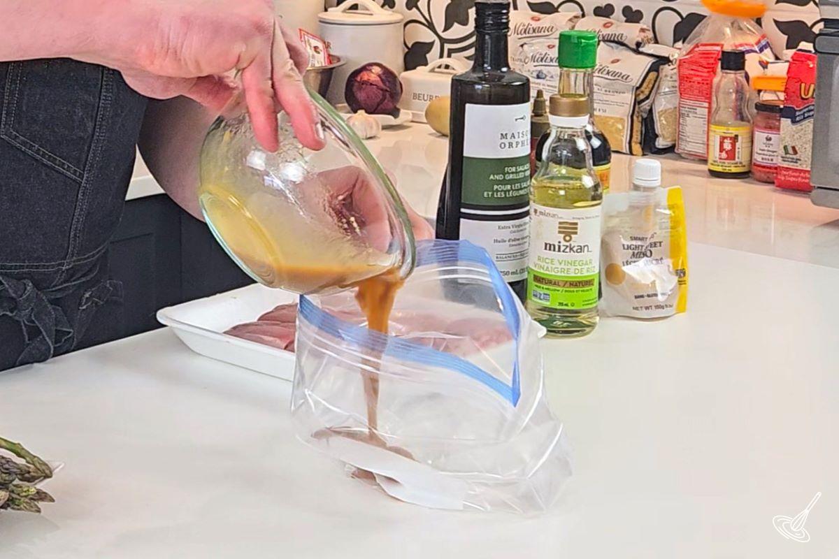 Someone pouring marinade in a sealable plastic bag.