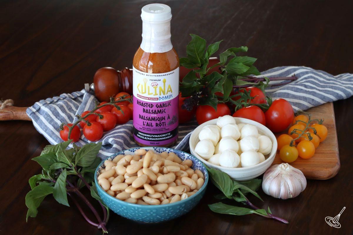Ingredients in bowls including, bocconcini cheese, white beans, tomatoes, garlic, and basil.