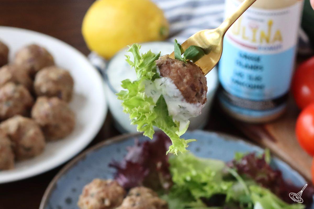 A fork holding a Greek lamb meatball dipped in tzatziki.