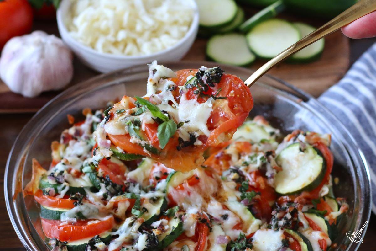 Someone taking a spoonful of Caprese Zucchini Casserole. 
