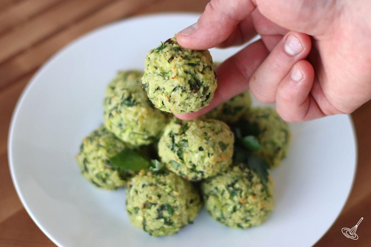 Someone taking a zucchini garlic bite from a plate.