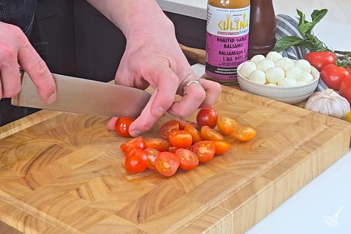 Someone cutting cherry tomatoes in half.