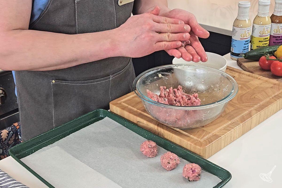 Someone rolling meatballs by hand.