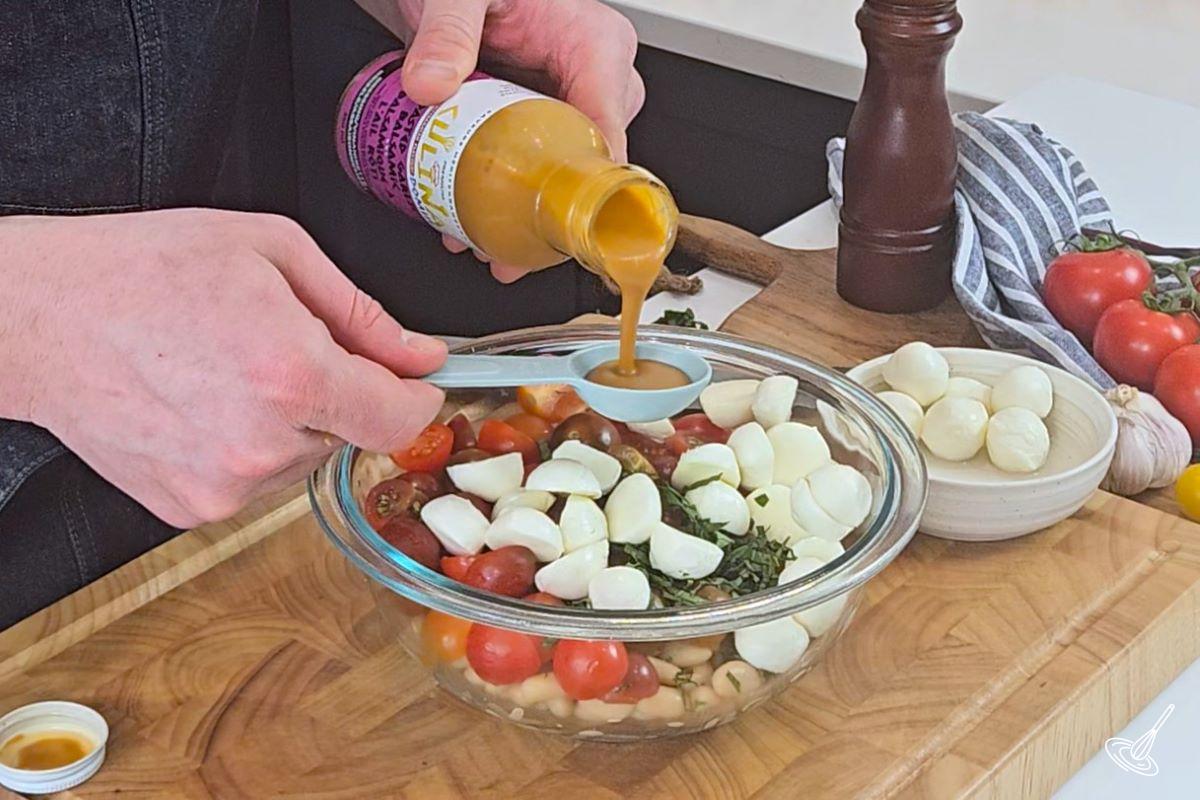 Someone pouring salad dressing in a measuring spoon.