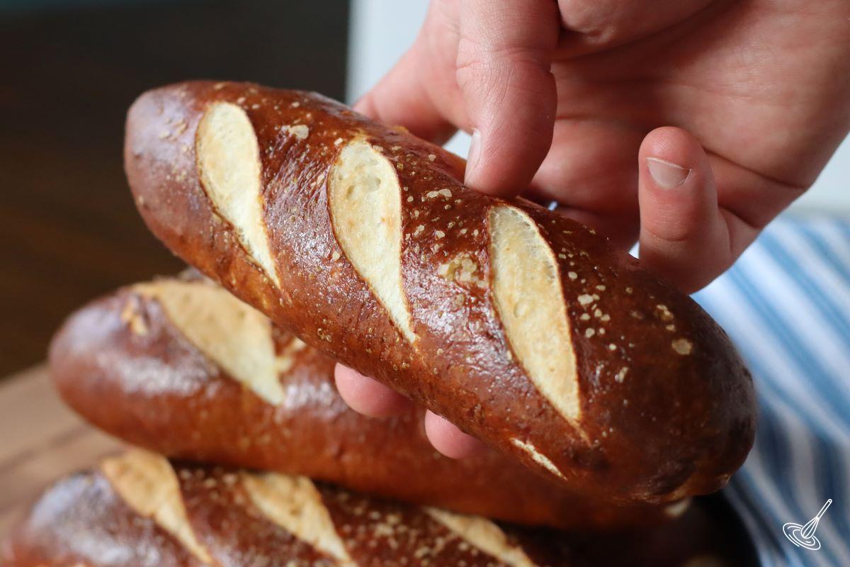 Someone holding a Pretzel Hot Dog Bun.