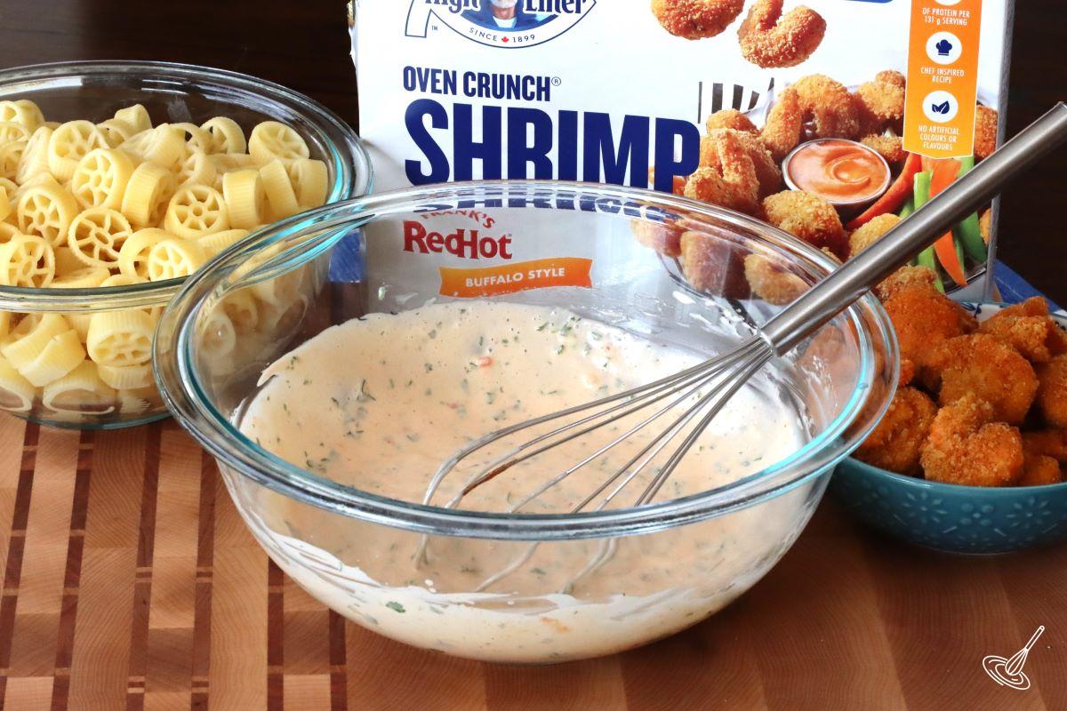 Salad dressing in a bowl with a whisk. 