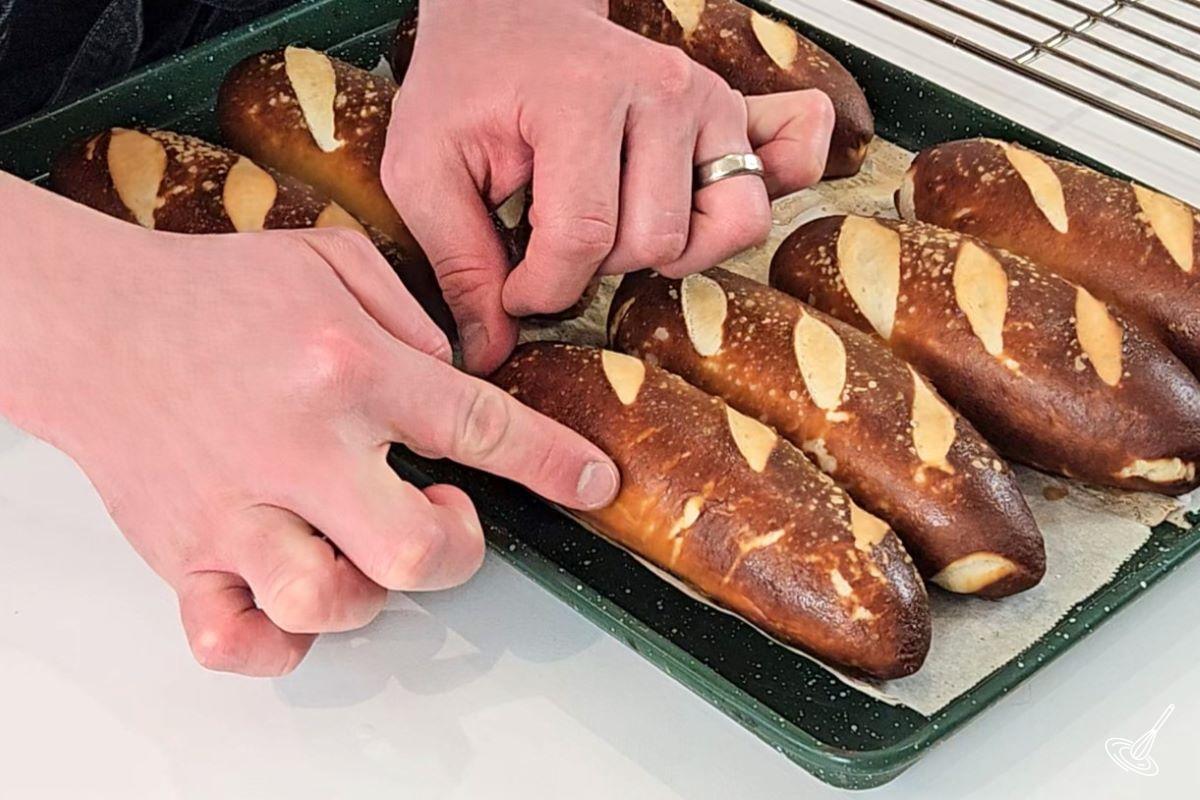 Baked pretzel hot dog buns on a tray.