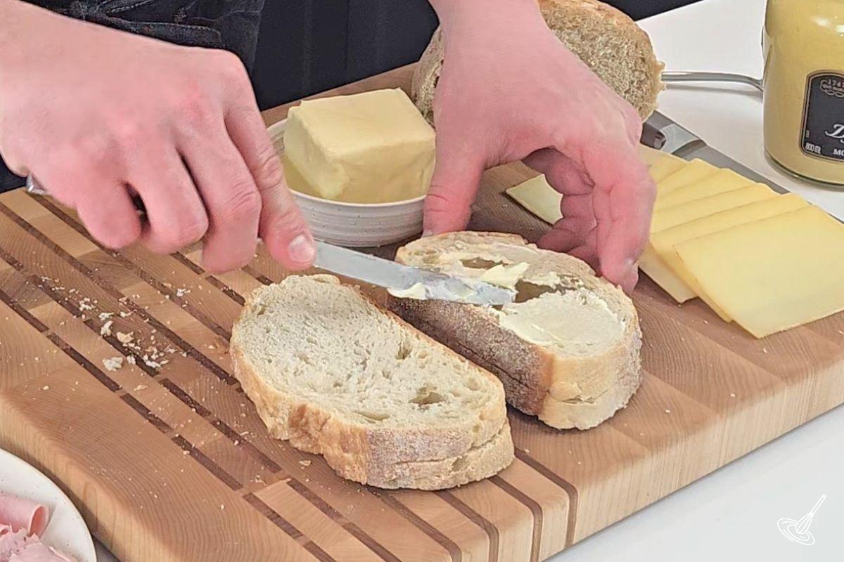Someone spreading butter over sliced bread. 