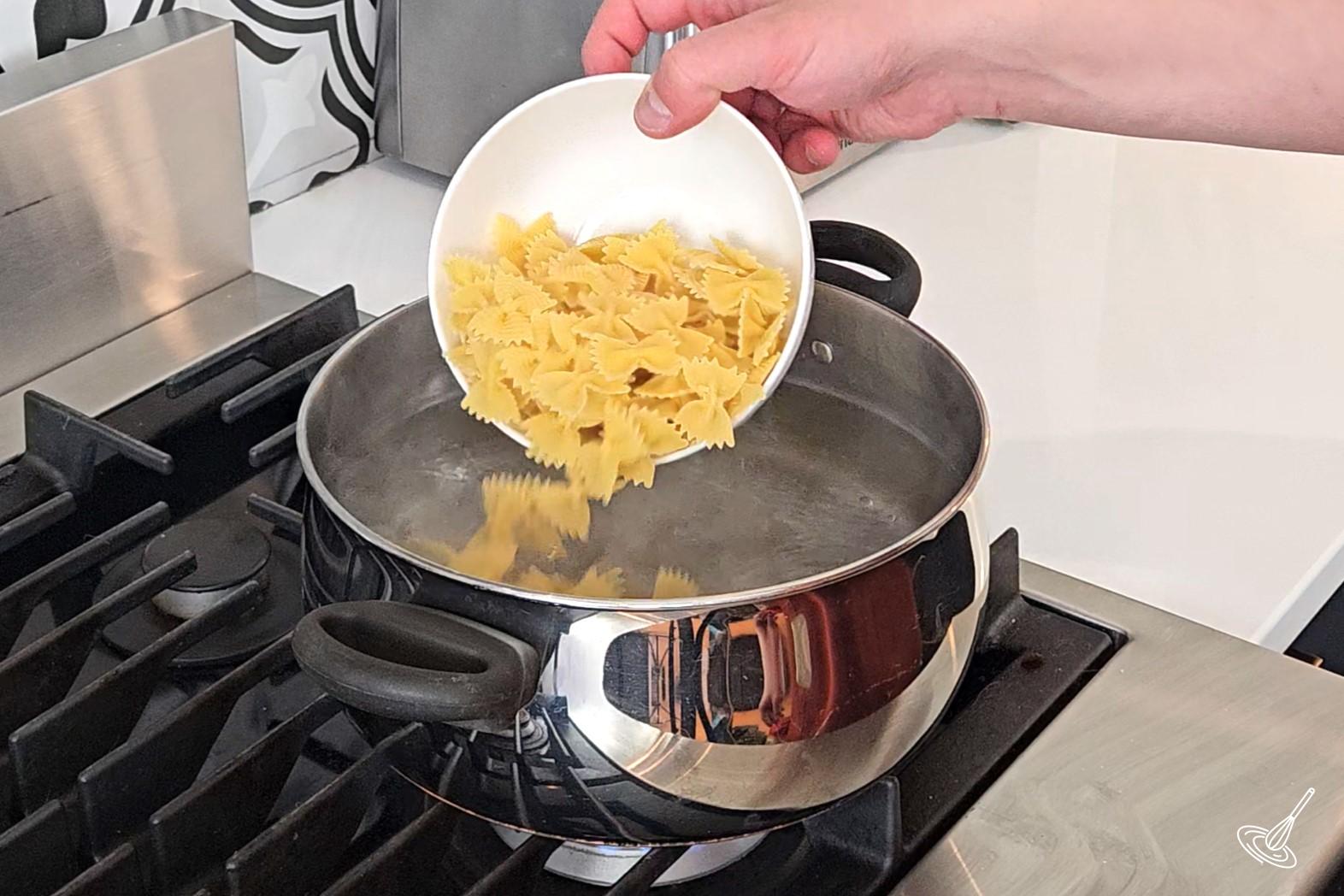 Someone placing pasta in a large pot of boiling water.