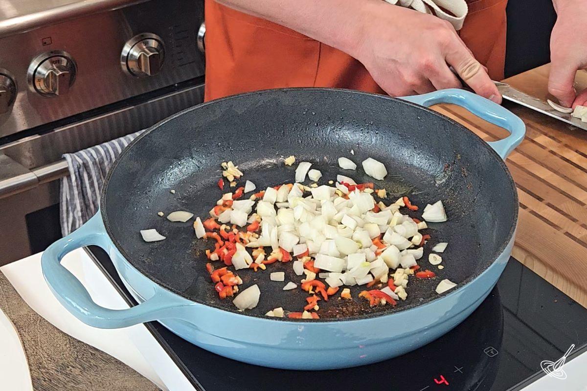 Chopped onion, fresno pepper, and garlic, cooking in a skillet.