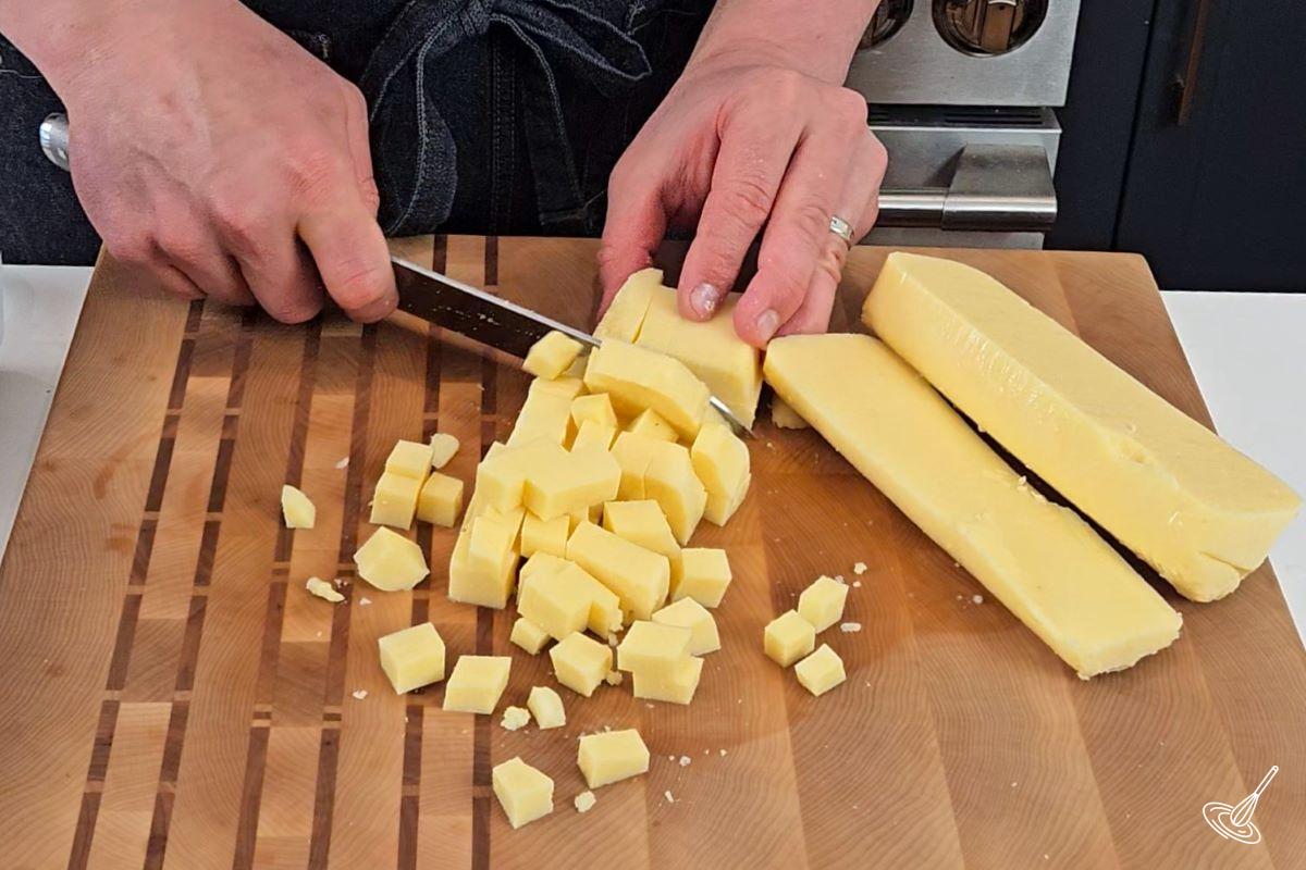 Someone cutting a tube of cooked polenta into ½ inch cubes. 