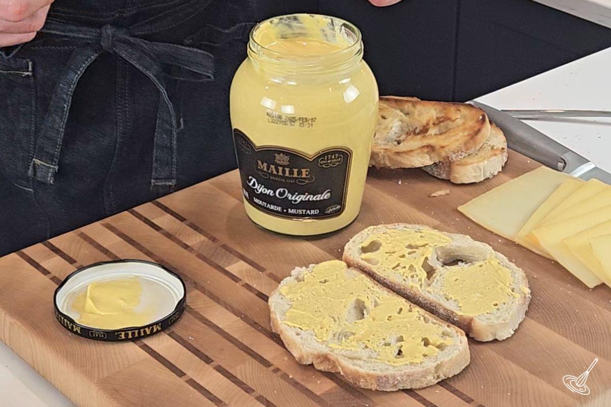 Dijon mustard being spead over slices of bread.