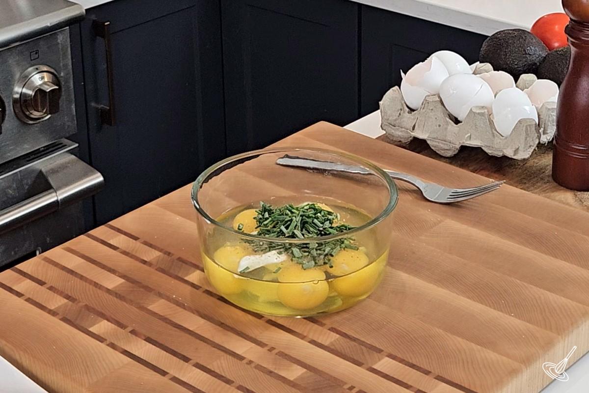 A bowl containing eggs and chopped chives. 