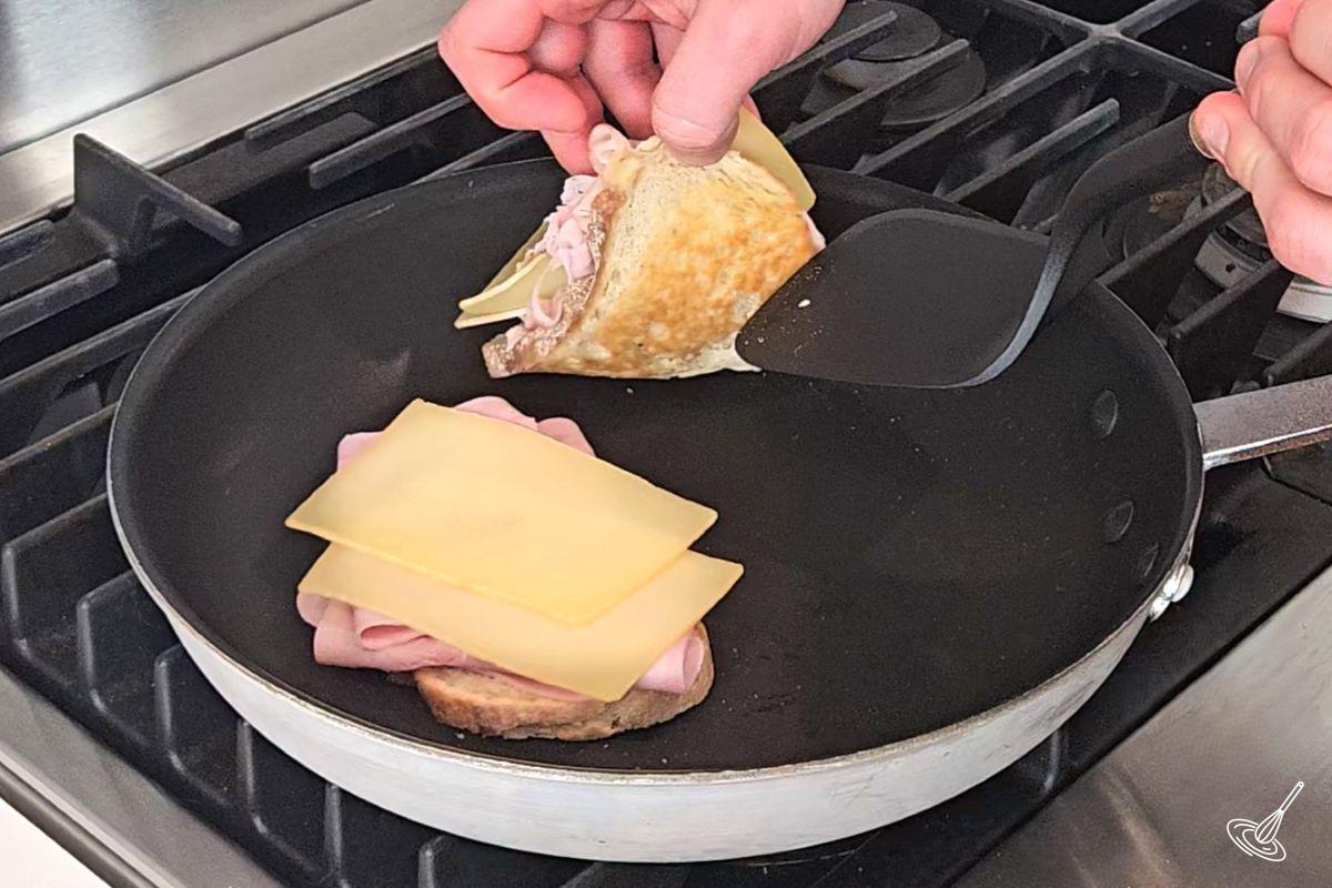 Raclette sandwiches being grilled in a frying pan.