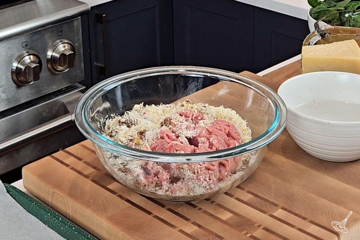 Ingredients to make meatballs in a large glass bowl.