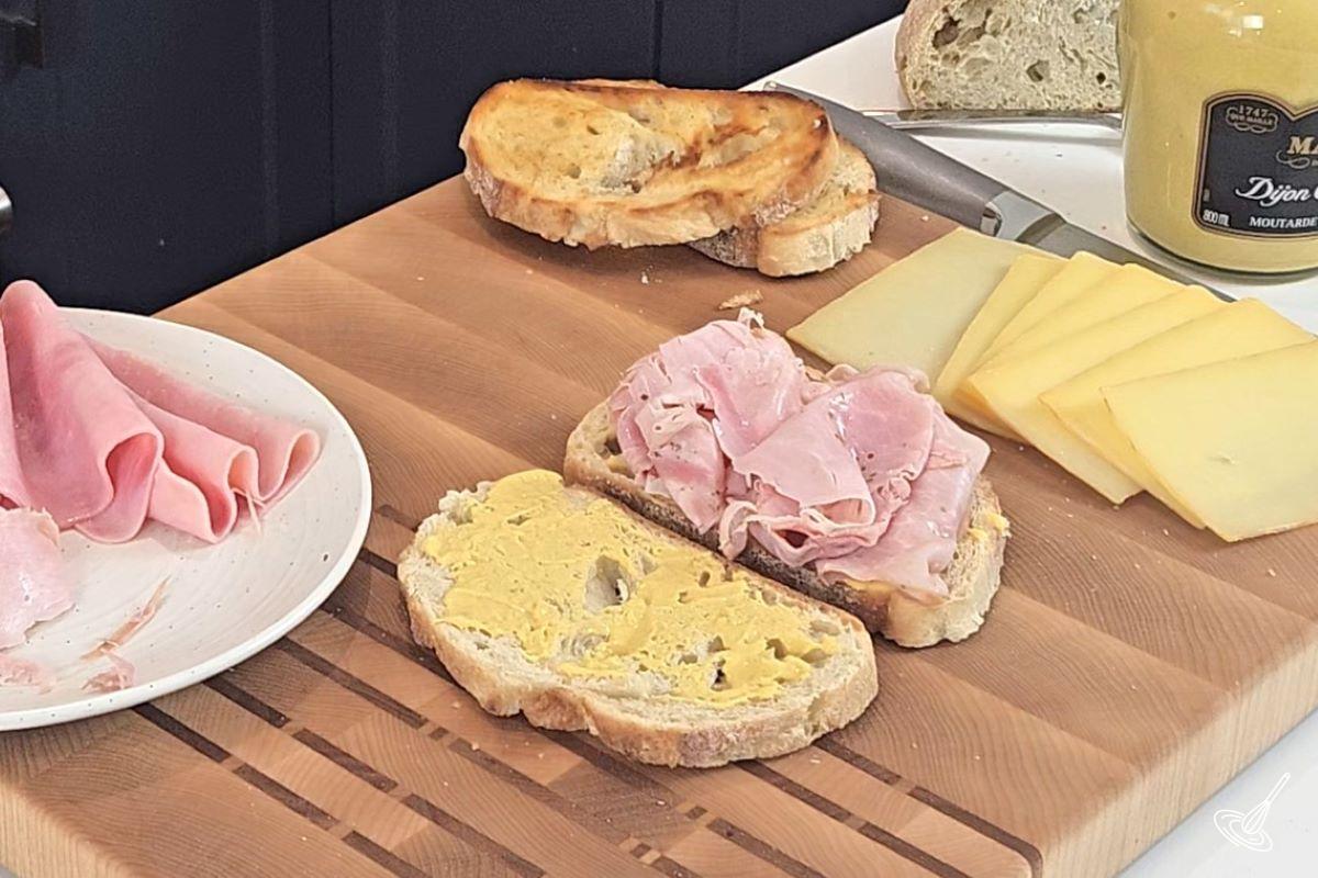 Someone placing sliced of ham on a sandwich.