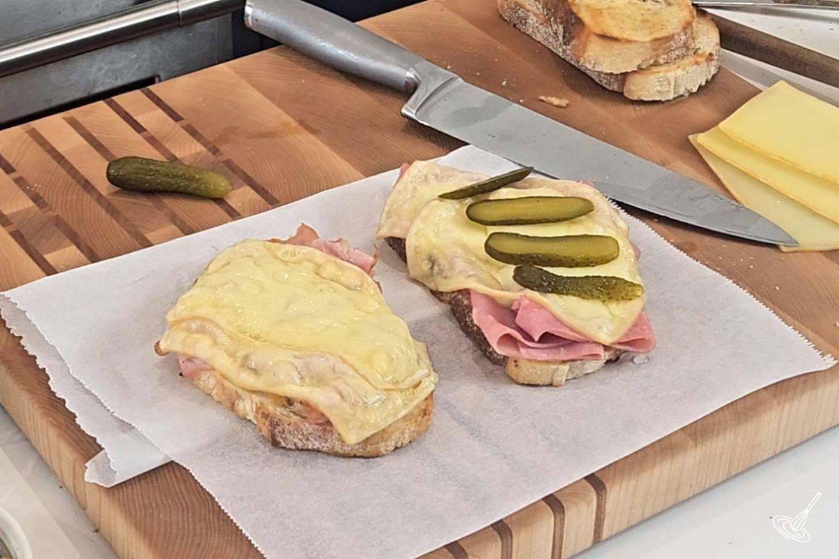 Sliced of gherkin pickles being placed on a sandwich.