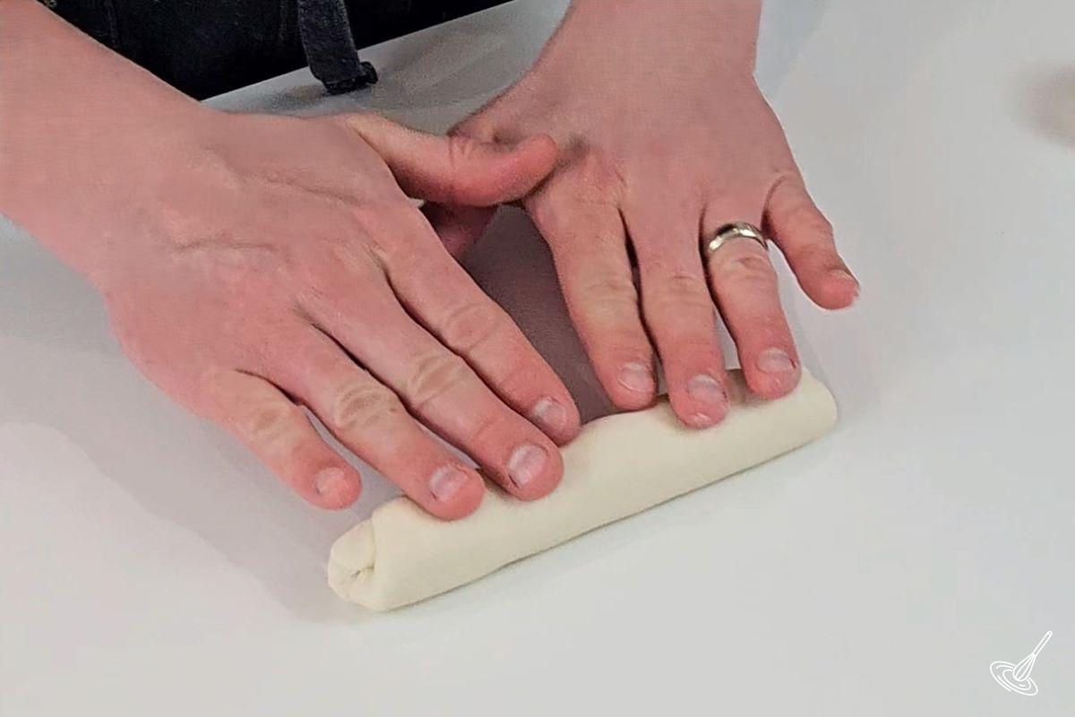 Someone rolling dough into a log. 