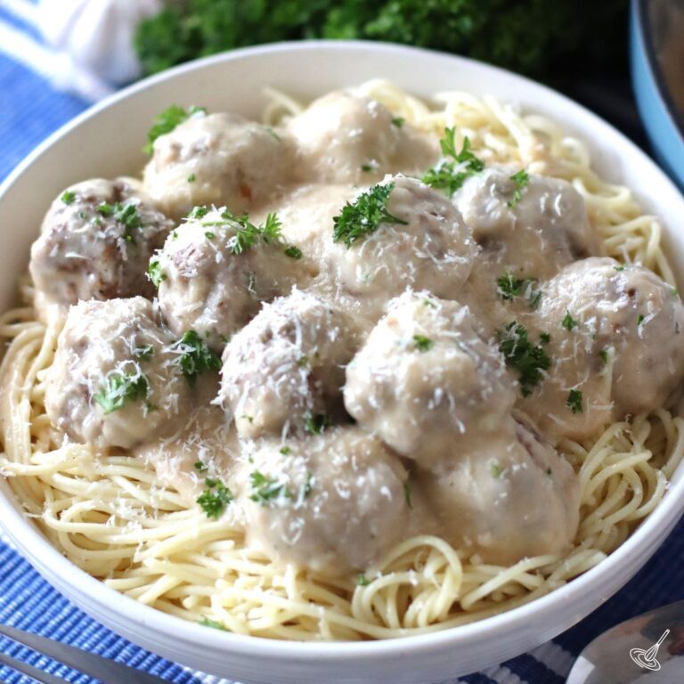 Alfredo Meatballs over spaghetti in a bowl.