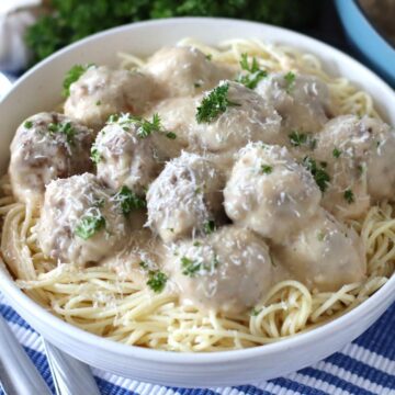 Alfredo Meatballs over spaghetti in a bowl.