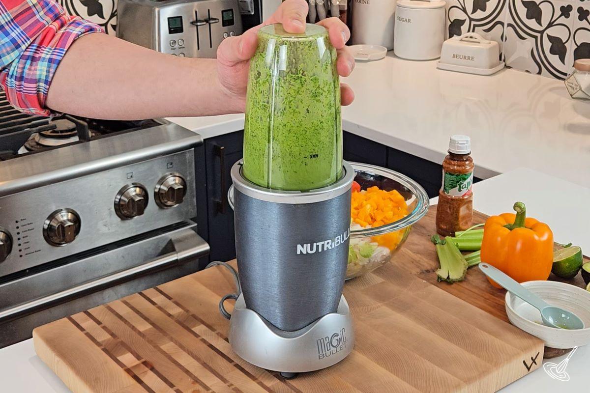 Someone blending cilantro and oil in a blender.