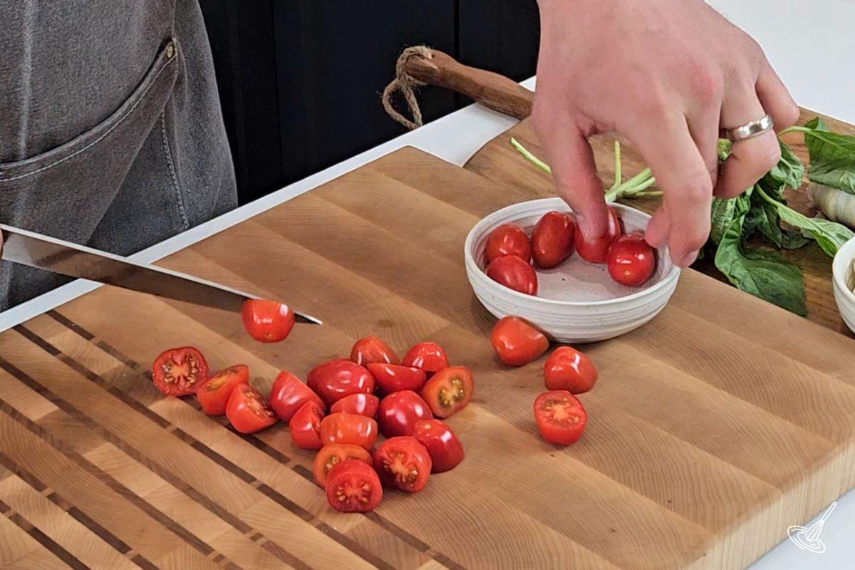 Someone cutting cherry tomatoes in half.