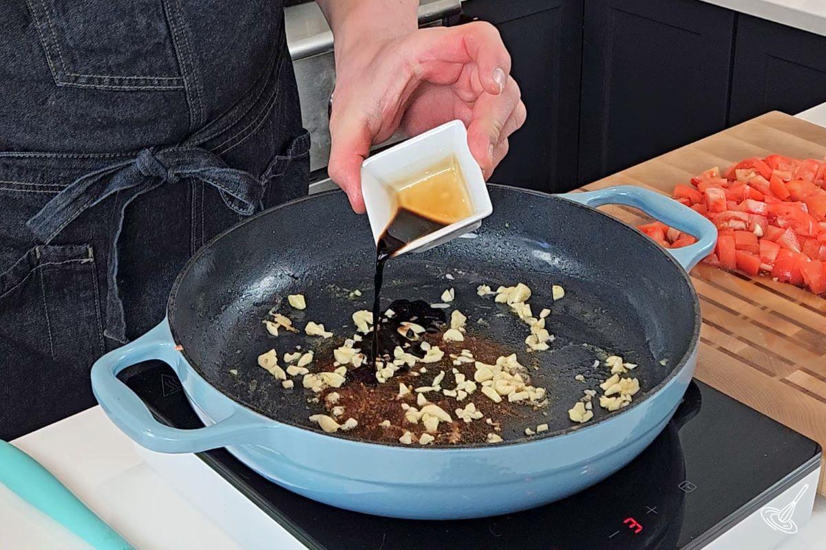 Someone deglazing a skillet with balsamic vinegar.
