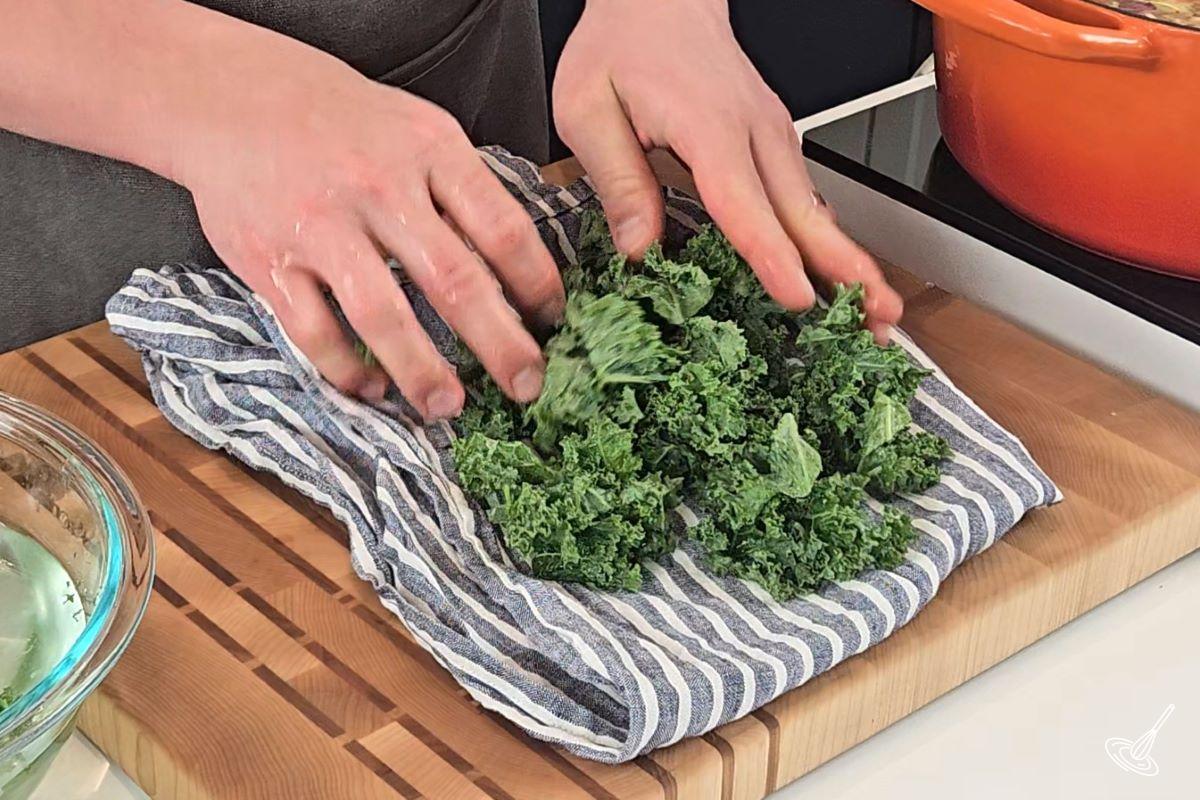 Someone drying off kale on a kitchen towel.