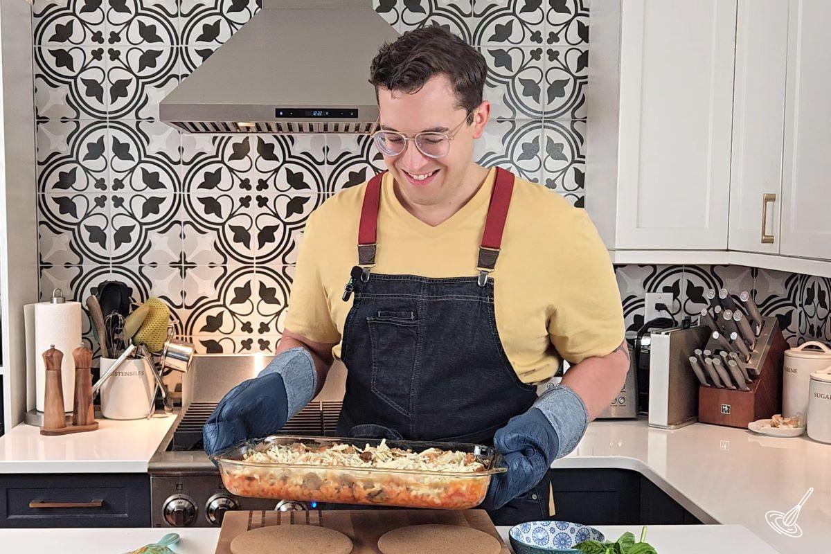 Someone holding a casserole dish with oven mitts. 