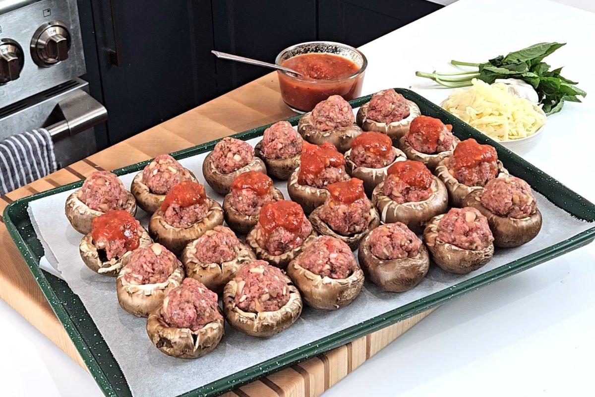 Someone adding marinara sauce on top of Mushroom stuffed meatballs. 