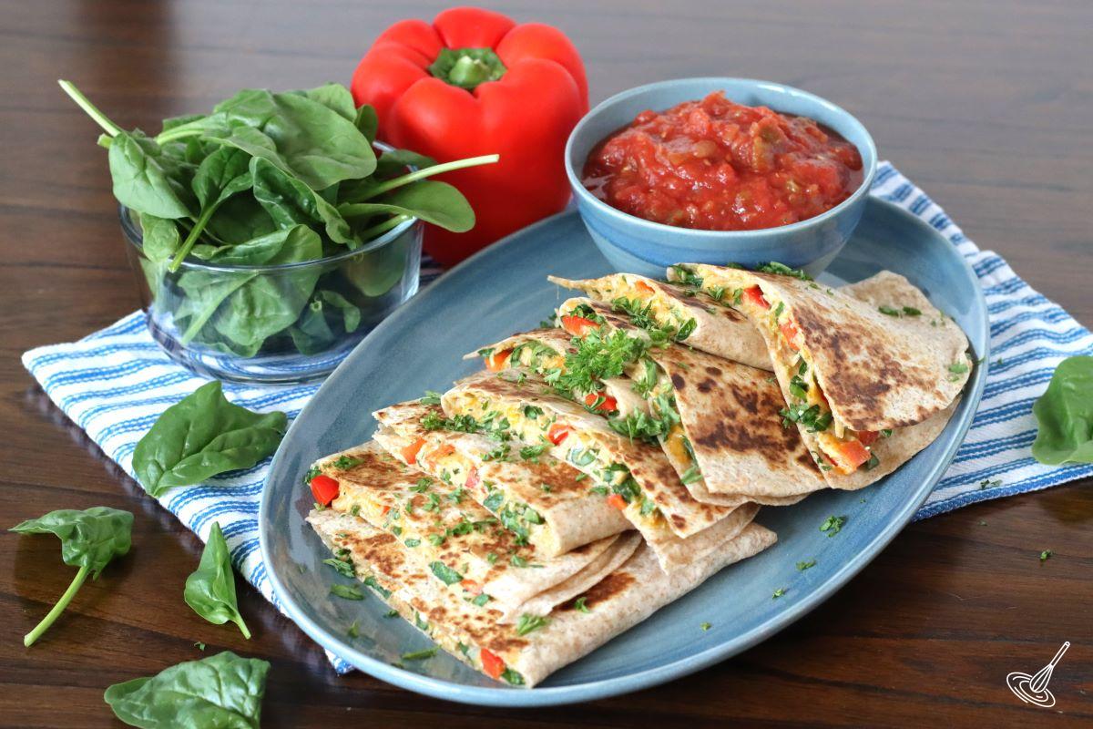 Chicken Spinach Quesadillas on a serving platter with a small bowl of salsa.