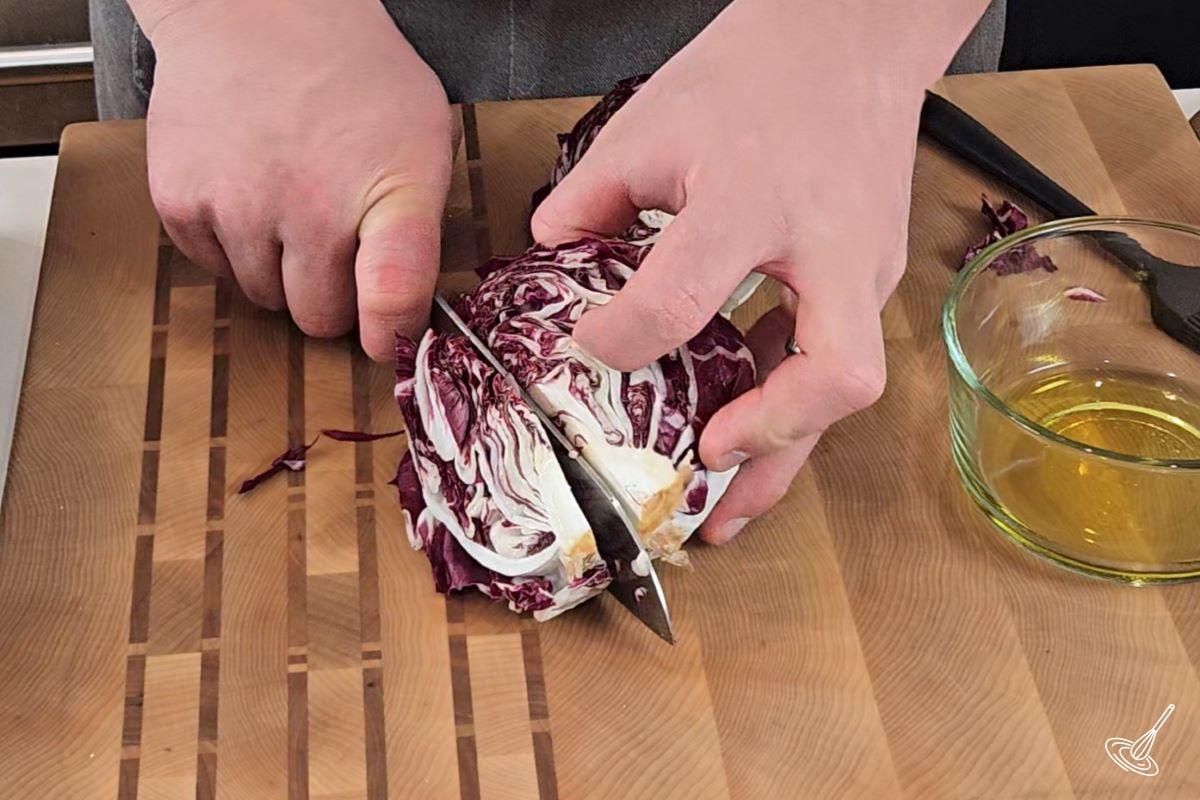 Someone cutting a head of radicchio in hald. 