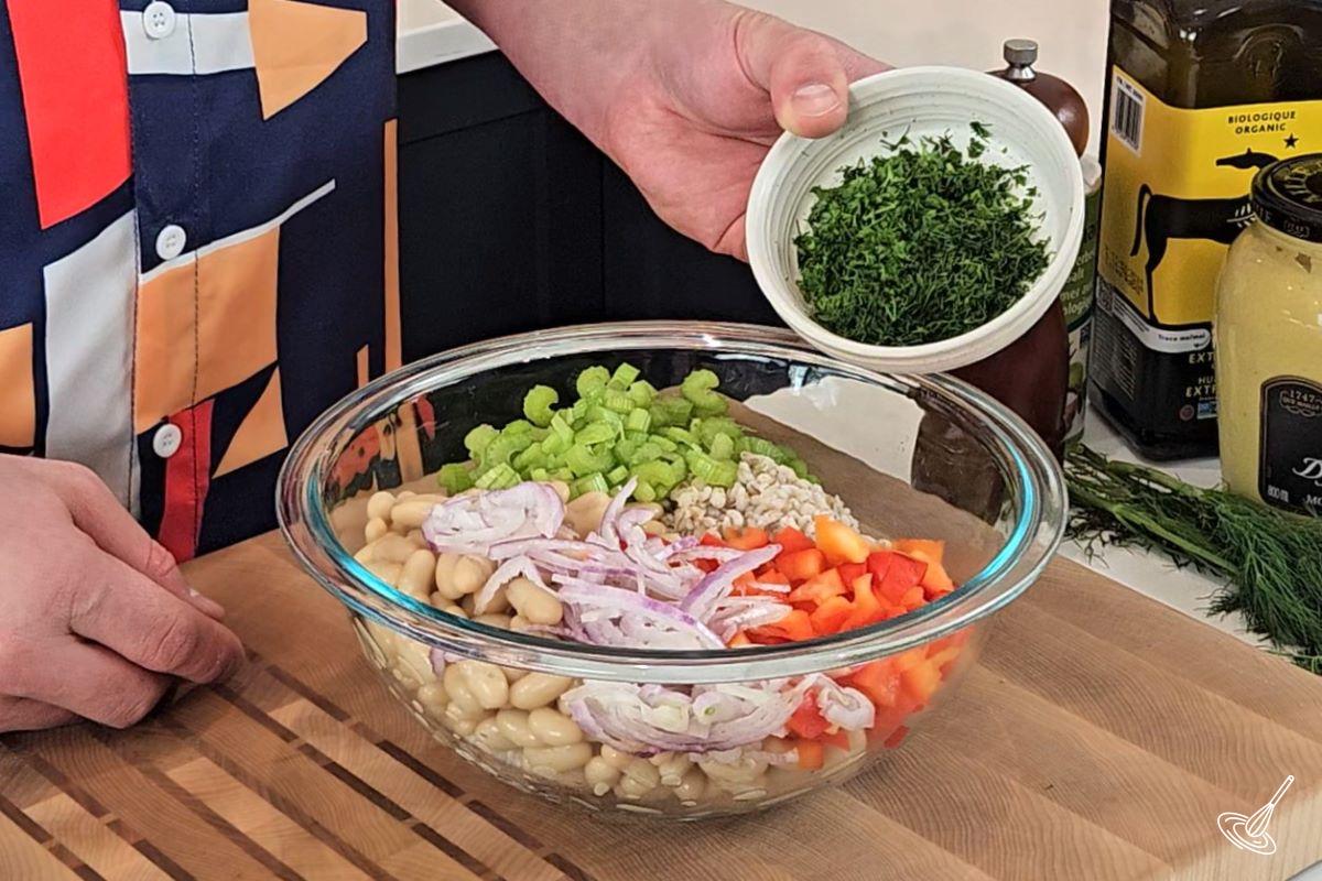 Someone adding chopped fresh herbs to a salad. 