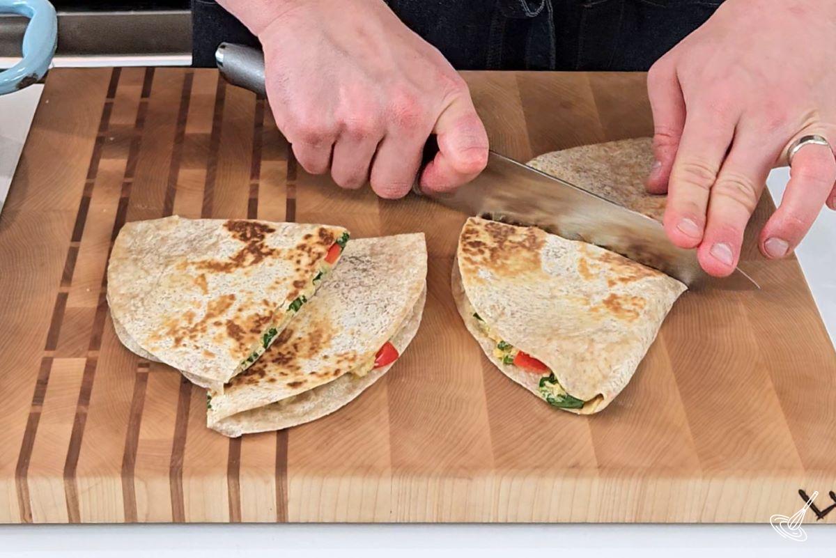 Someone cutting a quesadilla in half.