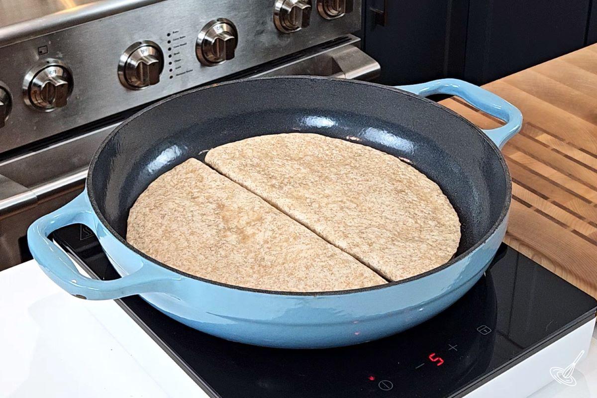 Two quesadillas cooking in a skillet pan.