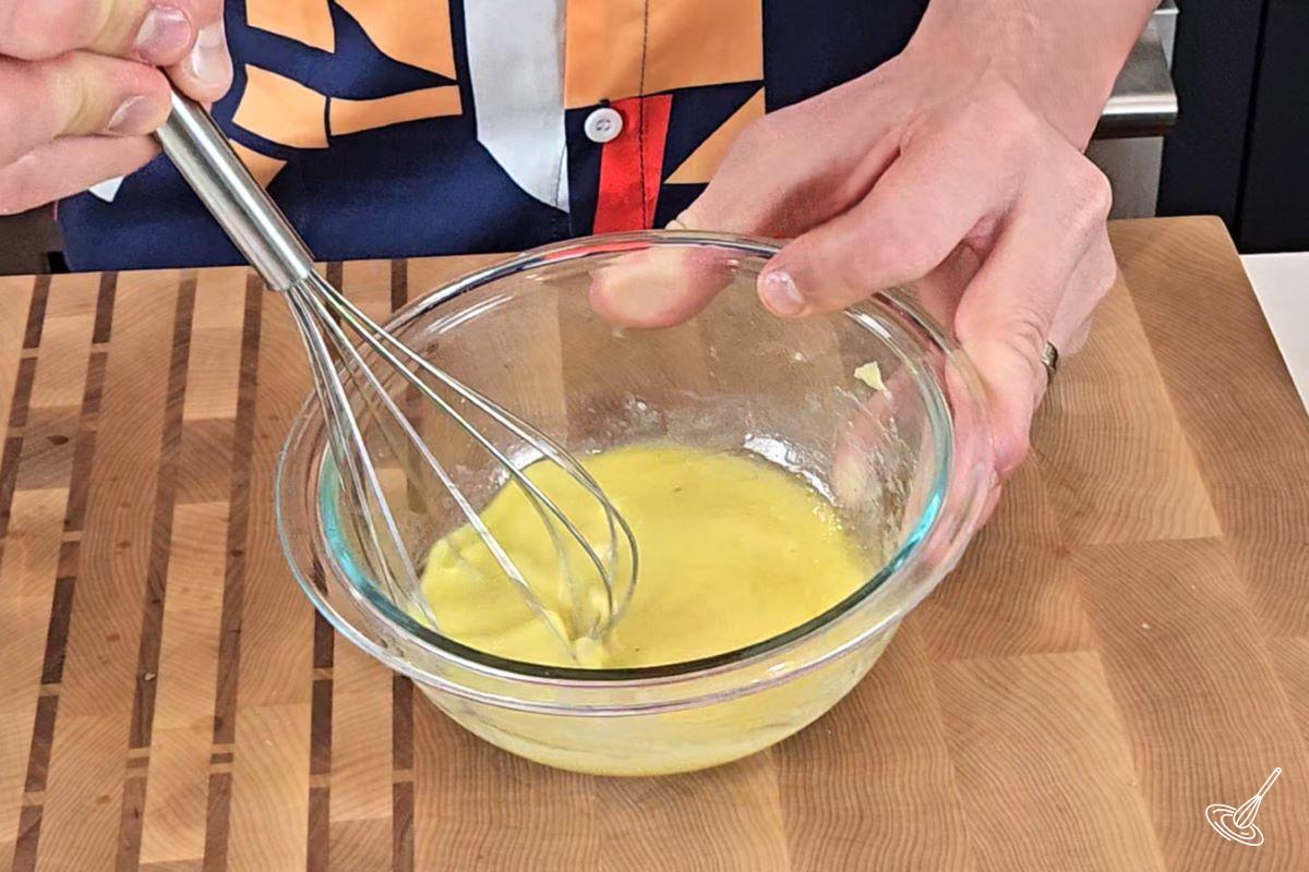 Someone using a whisk to make a salad dressing. 