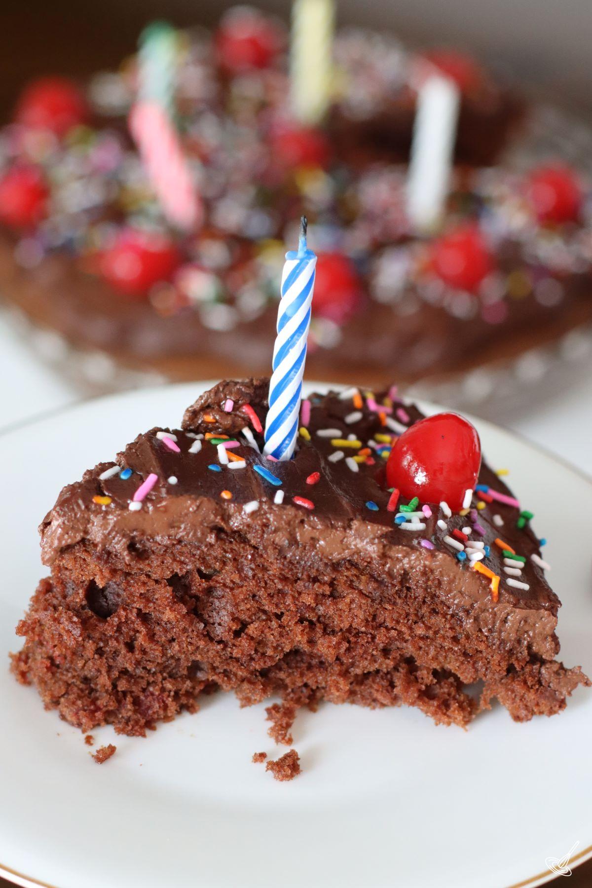 A slice of Chocolate Cherry Cake with a candle on top.