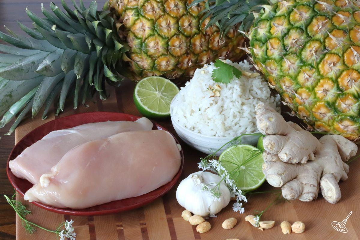 Chicken Breasts on a plate, beside a bowl of cooked rice and a ginger root.