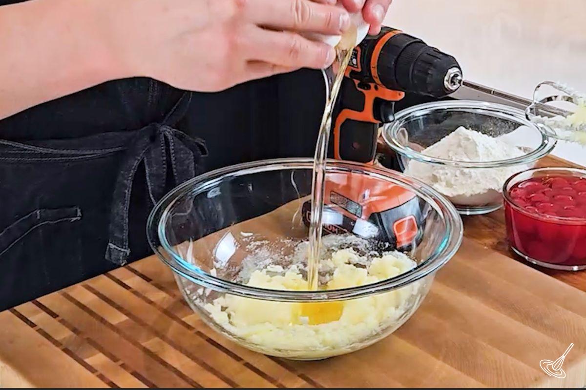 Someone cracking an egg in a large bowl. 