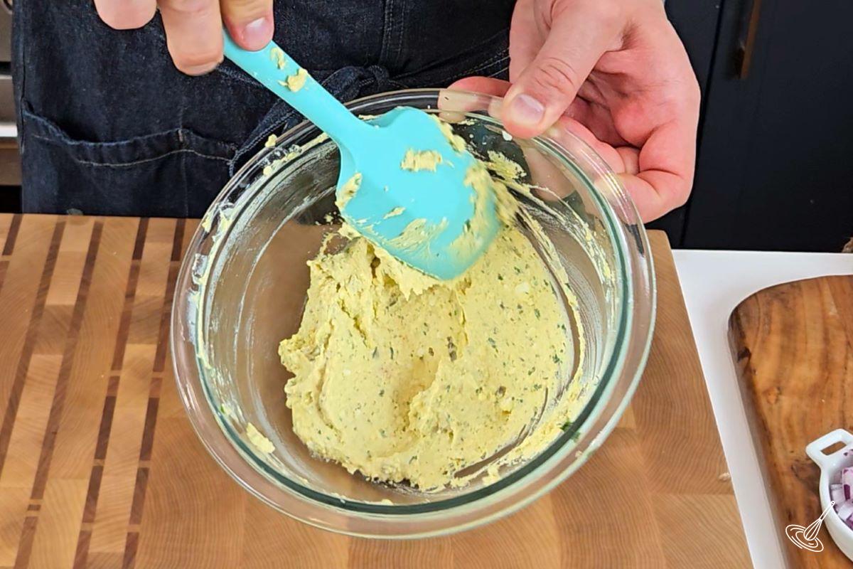 Someone mixing the egg yolk mixture with a spatula. 